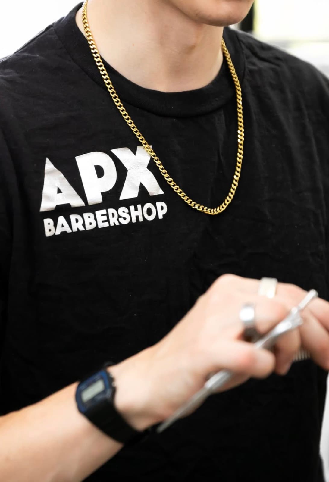 APX Barbershop shirt, gold chain, and shears between cuts